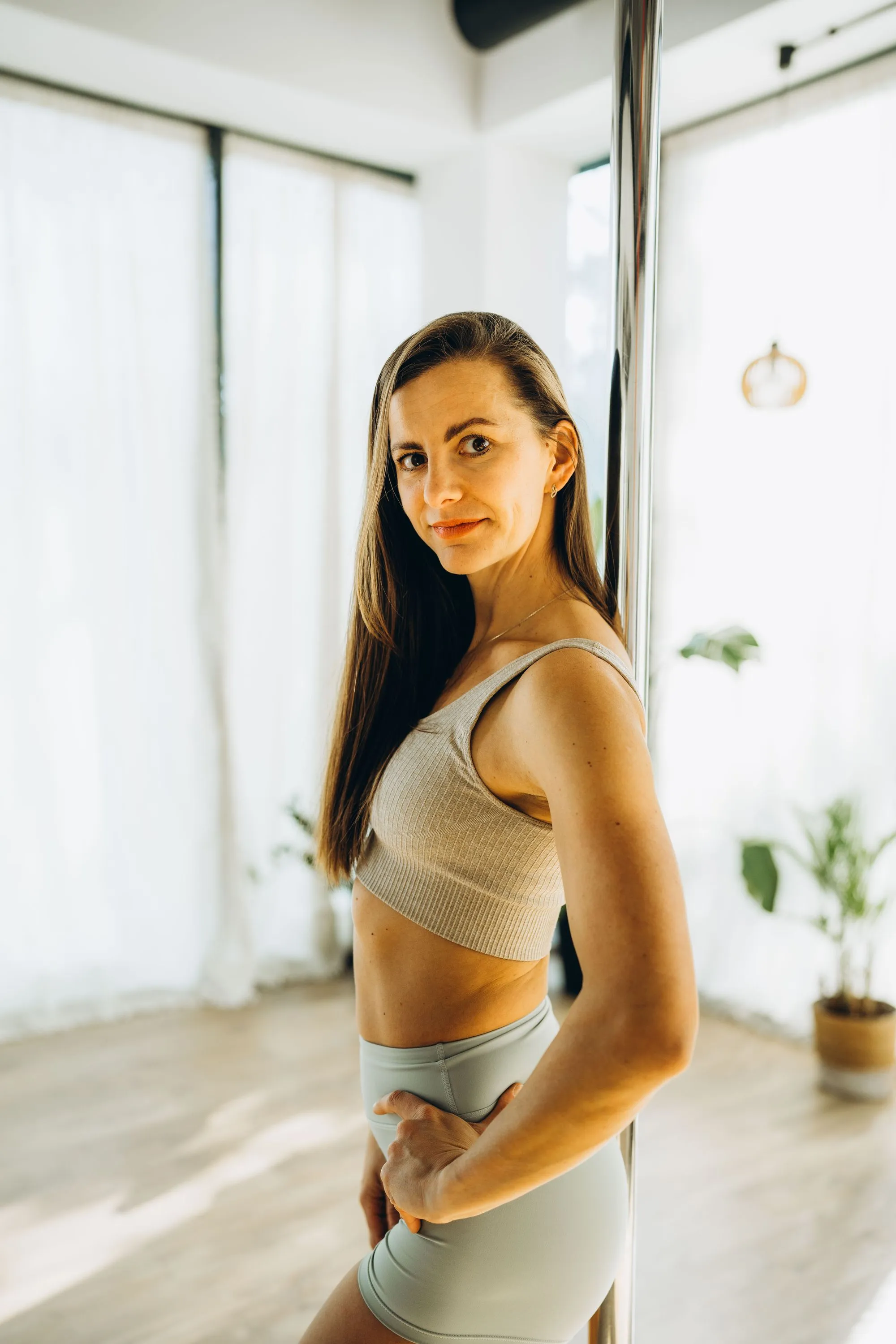 Kobieta przy rurce do pole dance w jasnej sali Balance Studio